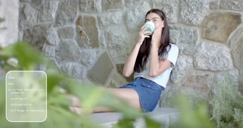 Woman sipping from mug, code overlay moving across stone bench garden to show Stock Footage 316965544