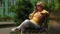 Woman sits on the bench and communicates via smartphone HD Footage