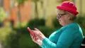 Woman sits on the bench and uses red cell phone HD Footage