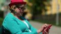 Woman sits on the bench and uses red cell phone HD Footage