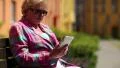 Woman sits on the bench in courtyard and uses white smartphone HD Footage
