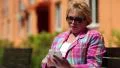 Woman sits on the bench in courtyard and uses white smartphone HD Footage