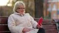 Woman sits on the bench near the road and communicates via smartphone HD Footage