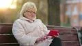 Woman sits on the bench near the road and uses red cell phone HD Footage
