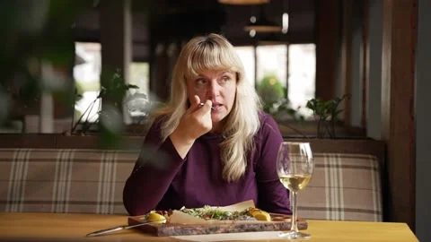 A woman sits in a cafe, eats fish and drinks wine Stock-Footage 234656990