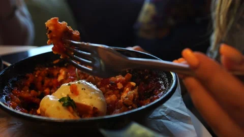 Woman sits in cafe, eats hot food, picks up food with a fork, approaches a plate Stock Footage 138895868