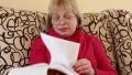 Woman sits on a couch and flips through the pages of big book HD Footage