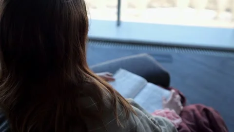 Woman sits on couch and holds with hands open paper book Stock Footage 330104341