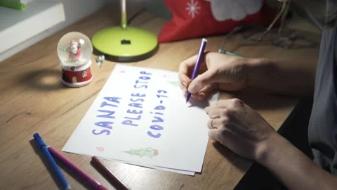 A woman sits down at a table and decorates a poster of a child for Santa Claus Stock Footage 143955821