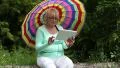 Woman sits on a fallen tree and uses tablet PC HD Footage