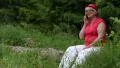 Woman sits on a fallen tree in the forest and communicates via smartphone HD Footage