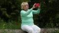 Woman sits on a fallen tree in the forest and makes photos on his smartphone HD Footage