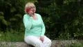 Woman sits on a fallen tree in the forest and communicates via smartphone HD Footage