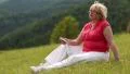 Woman sits on a green grass and and listens to music HD Footage