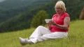 Woman sits on a green grass and uses smartphone HD Footage