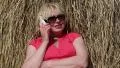 Woman sits near haystack and communicates via mobile phone HD Footage