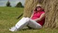 Woman sits near haystack and communicates via mobile phone HD Footage