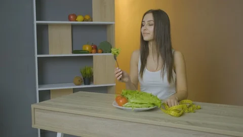 Woman sits at a table and eats cabbage leaves adheres to a diet Stock Footage 128646080