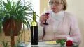 Woman sits at a table drinking red wine and eating cheese HD Footage