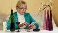 Woman sits at the table, drinks red wine and uses smartphone HD Footage
