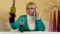Woman sits at the table, drinks red wine and speaks on smartphone HD Footage