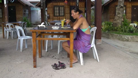 A woman sits at a table in the restaurant, eats and drinks cocktail Stock Footage 91367810