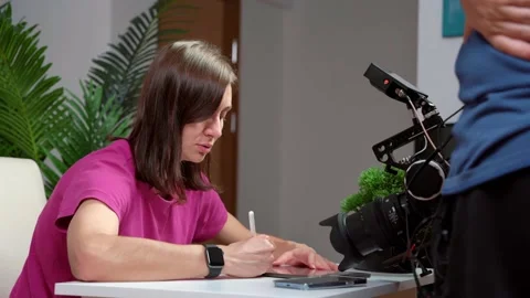 Woman sits at table on set talking to operator video camera, coordinating script Stock Footage 219836625
