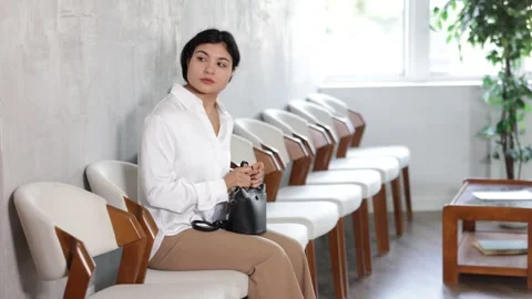 Woman sits in waiting room, queue awaiting Stock Footage 343712829