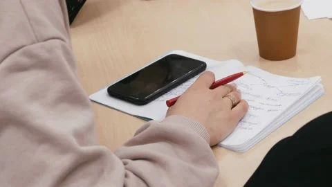 Woman sits at work table at workplace, closes female hands, using smartphone Stock Footage 155458337