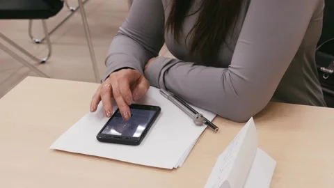 Woman sits at work table at workplace, closes female hands, using smartphone Stock Footage 155458380