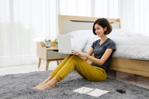 Woman sitting and using computer in bedroom Stock Photos