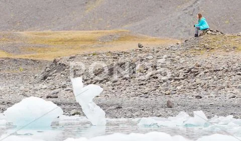 Woman sitting on the beach at Jokulsarlon glacier lagoon - Iceland Stock Photos