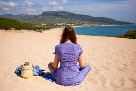 A woman sitting is on a beach near ocean Stock Photos