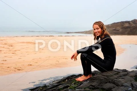 Woman Sitting On The Beach In Wetsuit