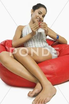 Woman sitting on a bean bag with a cup of coffee Stock Photos