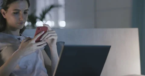 Woman sitting on bed and using her phone Stock Footage 168270078