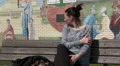 Woman sitting on bench gets cold, puts coat on HD Footage