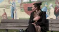 Woman sitting on bench getting hot in the sun HD Footage