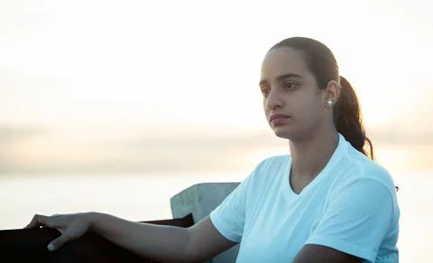 Woman sitting on a bench thinking, while watching the sunrise Stock Photos