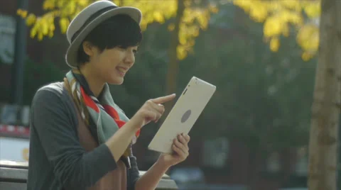 Woman Sitting On A bench Using A Digital Tablet (bike passes by) Stock-Footage 35287545