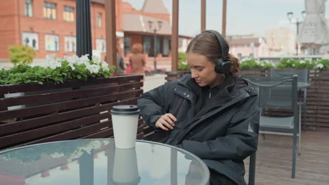 Woman sitting at cafe analyzing her schedule outside in fresh air, Female Vidéo 329564513