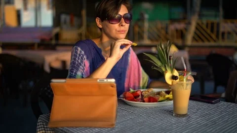 A woman sitting in a cafe at a table dunks potatoes in a sauce and eats Video stock 74621038