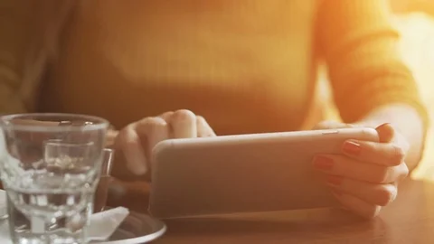 Woman sitting at the cafe table, typing on her mobile with her thin manicured Stock Footage 72068671