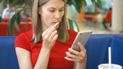 Woman sitting in cafe using her smartphone, chatting with friends eating french Stock Footage 76980284