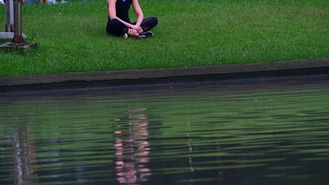 A Woman sitting calmly at park near pool Stock Footage