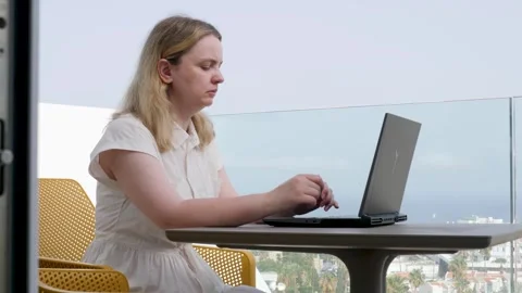 A woman is sitting comfortably at a table using her laptop computer Stock Footage 317018463