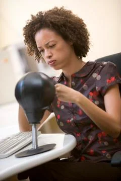 Woman sitting in computer room punching a small punching bag Stock Photos