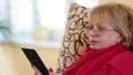 Woman sitting on a couch and reading electronic book. Woman with e-book HD Footage