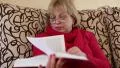 Woman sitting on a couch flipping through the pages of a big book HD Footage
