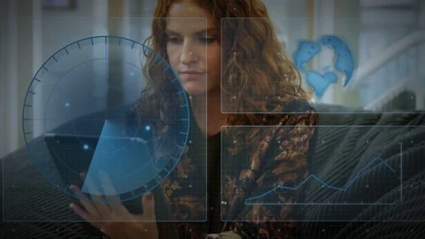 Woman sitting on couch holding tablet tapping screen reviewing tech HUD chart Stock Footage 332642453